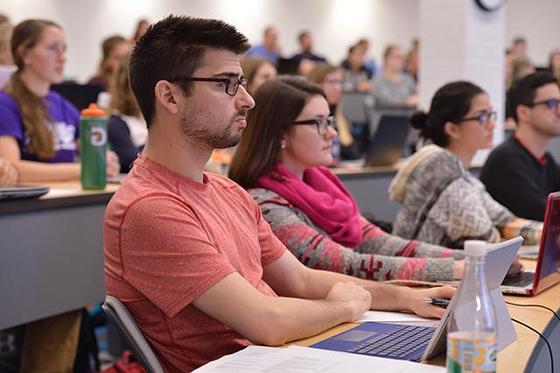 Photo of a group of students seated in a lecture classroom, paying attention to an offscreen instructor