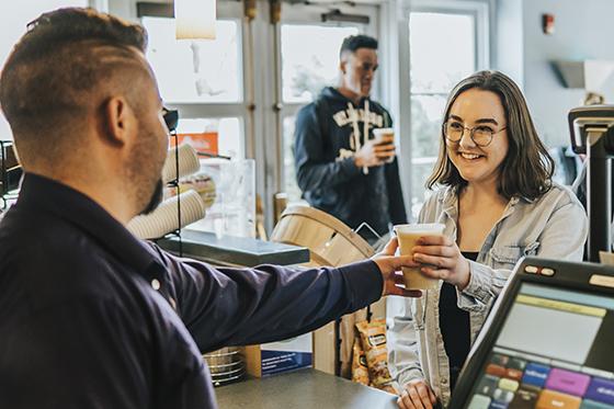 Photo of cafe employee handing a Chatham student a coffee in Cafe Rachel